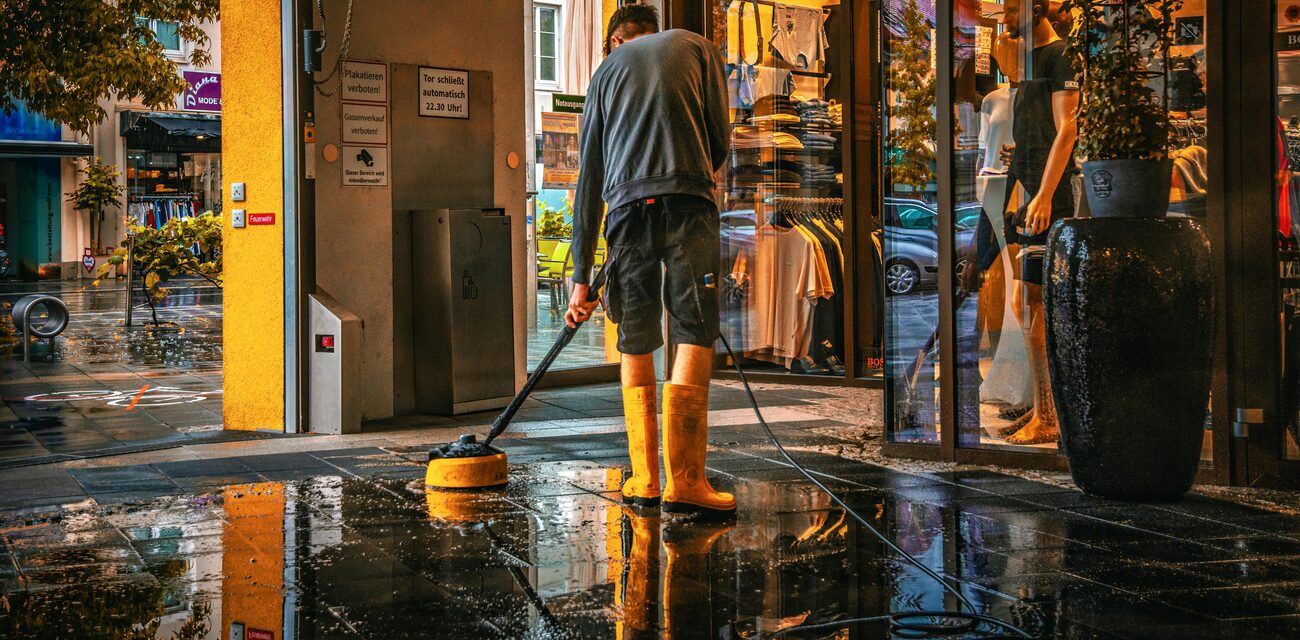 Worker power washing a storefront entrance